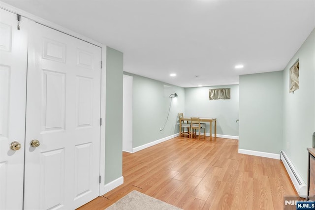 basement featuring a baseboard heating unit and light hardwood / wood-style flooring