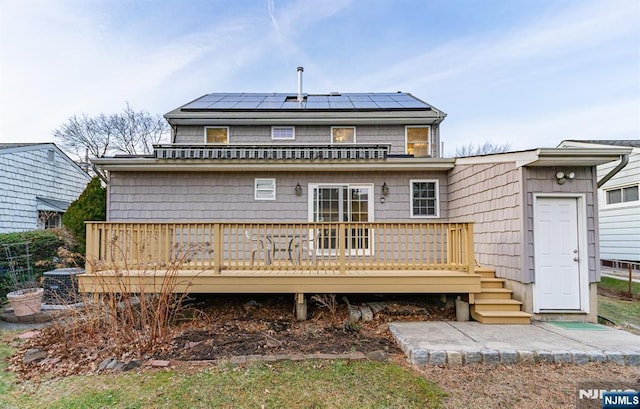 back of house with a wooden deck and solar panels