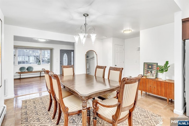 tiled dining room with a chandelier and baseboard heating