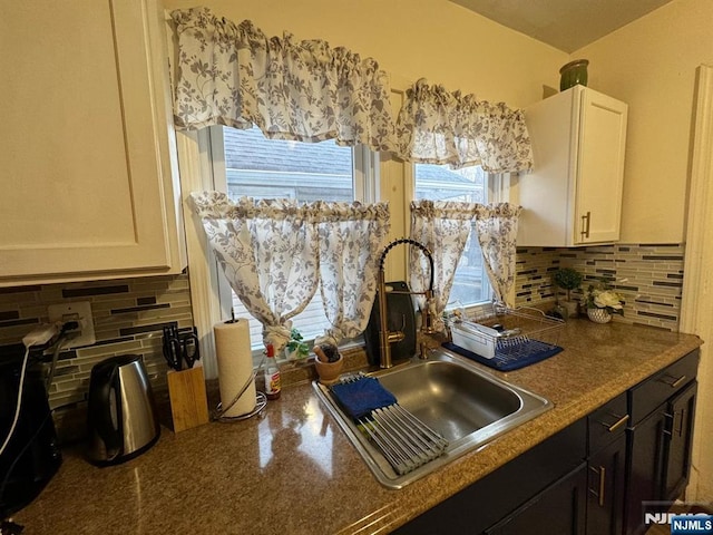 kitchen featuring white cabinetry, sink, backsplash, and dark brown cabinetry