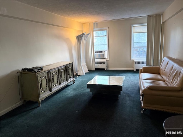 carpeted living room with cooling unit, radiator heating unit, and a textured ceiling