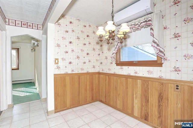 interior space featuring a baseboard heating unit, wooden walls, a chandelier, and a healthy amount of sunlight