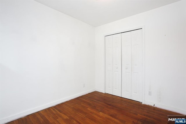 unfurnished bedroom with a closet and dark hardwood / wood-style floors