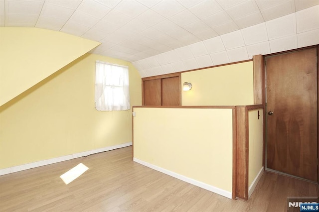 additional living space with vaulted ceiling and light hardwood / wood-style floors