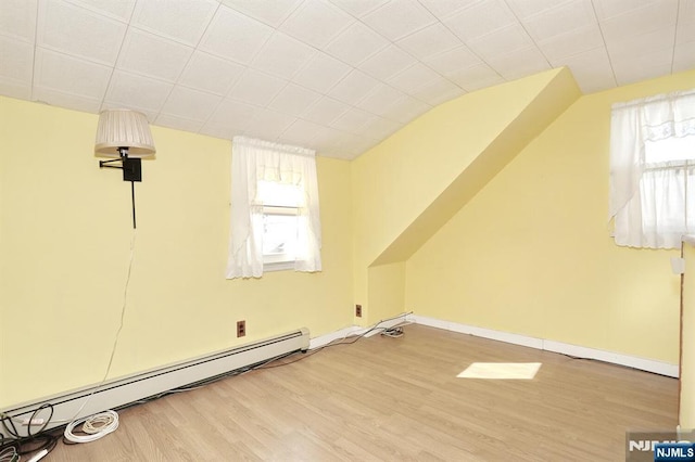 bonus room featuring a baseboard heating unit, vaulted ceiling, and hardwood / wood-style floors