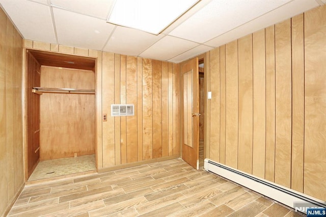 interior space with baseboard heating and wooden walls