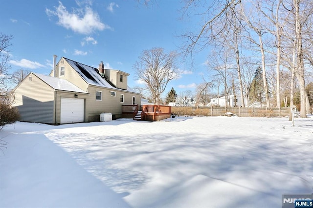 snow covered rear of property with a wooden deck