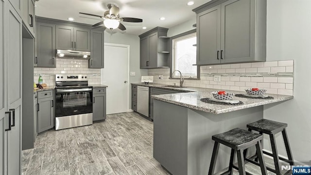 kitchen featuring sink, light hardwood / wood-style flooring, a breakfast bar, gray cabinetry, and stainless steel appliances