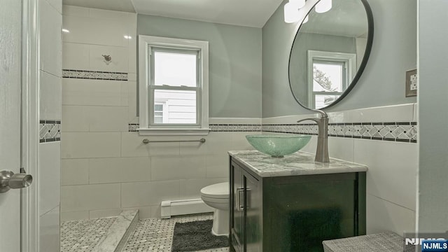 bathroom featuring a baseboard radiator, a wealth of natural light, and tile walls