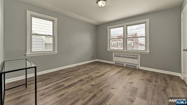 empty room with radiator heating unit and wood-type flooring