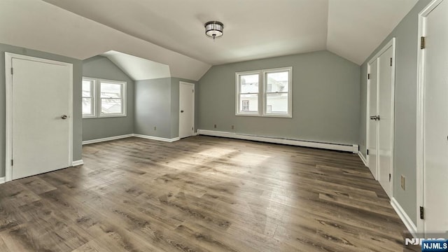 additional living space featuring lofted ceiling, plenty of natural light, dark hardwood / wood-style floors, and baseboard heating