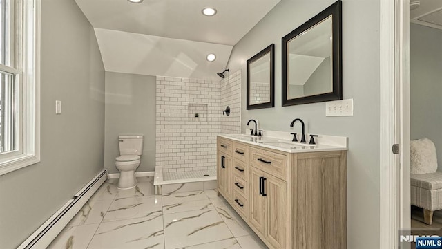 bathroom featuring toilet, vaulted ceiling, a tile shower, vanity, and a baseboard heating unit