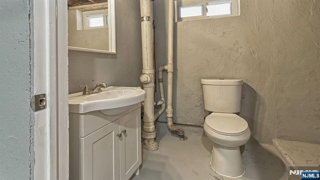 bathroom featuring vanity, concrete flooring, and toilet