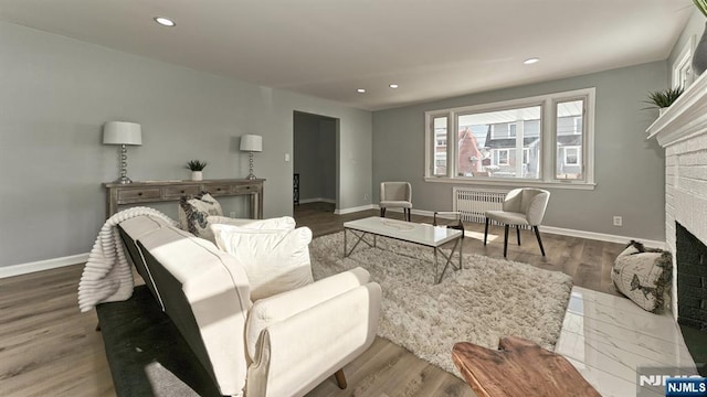 living room with dark wood-type flooring, radiator heating unit, and a fireplace