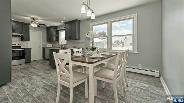 dining area with ceiling fan, sink, a wealth of natural light, and baseboard heating