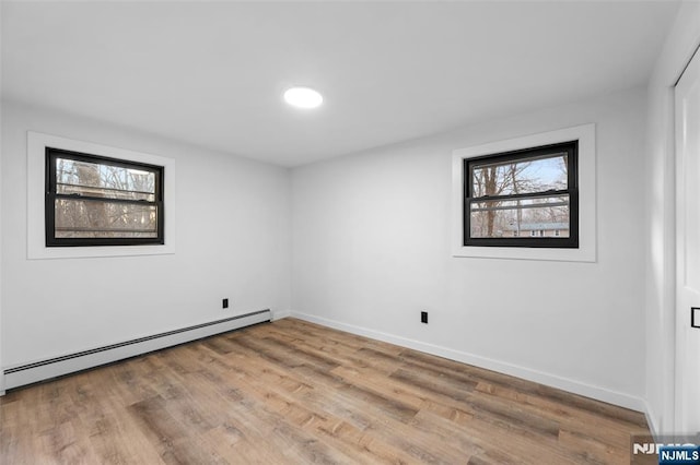 empty room with light hardwood / wood-style flooring and baseboard heating