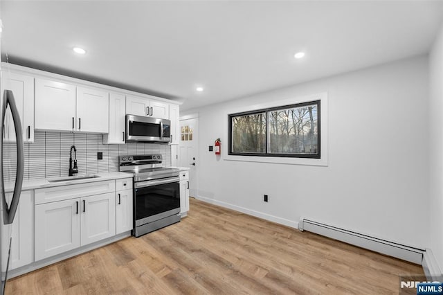 kitchen with white cabinetry, sink, stainless steel appliances, and a baseboard heating unit