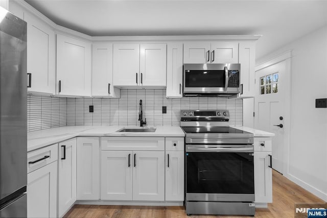 kitchen featuring sink, appliances with stainless steel finishes, tasteful backsplash, light stone counters, and white cabinets