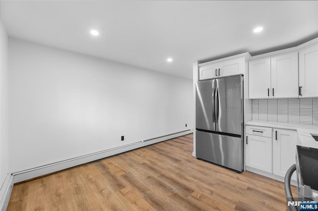 kitchen with white cabinetry, stainless steel fridge, a baseboard radiator, and light wood-type flooring