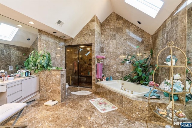 full bathroom featuring tile walls, lofted ceiling with skylight, separate shower and tub, vanity, and toilet