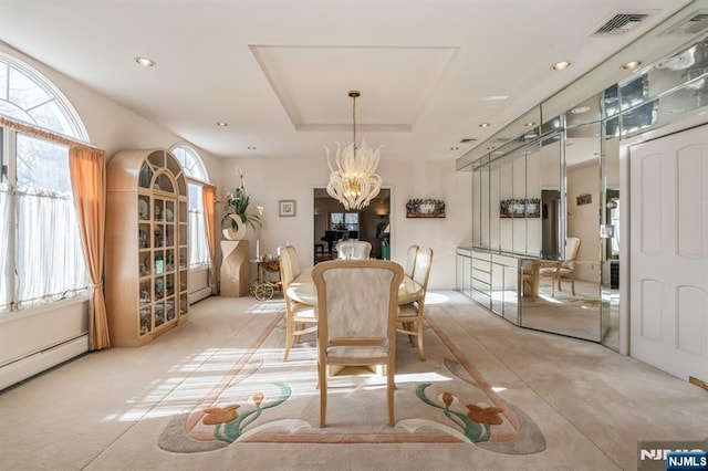 dining space with an inviting chandelier, a tray ceiling, and baseboard heating