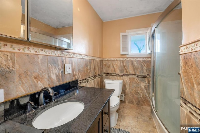 bathroom featuring tile walls, toilet, a shower stall, vanity, and tile patterned flooring