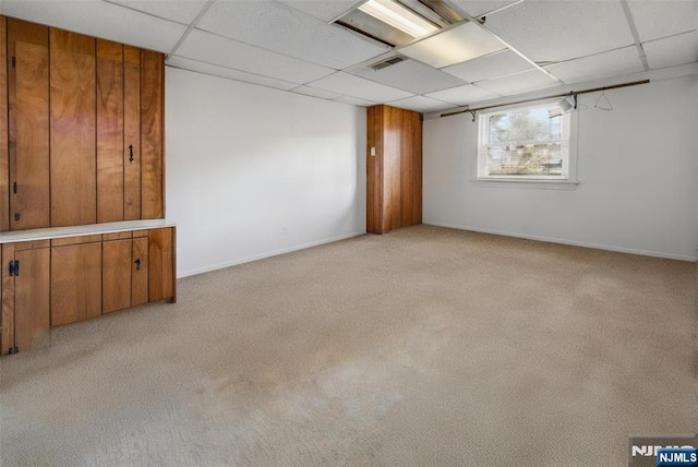 empty room featuring a paneled ceiling, light carpet, visible vents, and baseboards