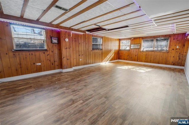 spare room featuring baseboards, wooden walls, visible vents, and wood finished floors