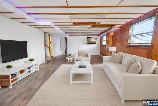 living area with stairway, wood finished floors, and wooden walls