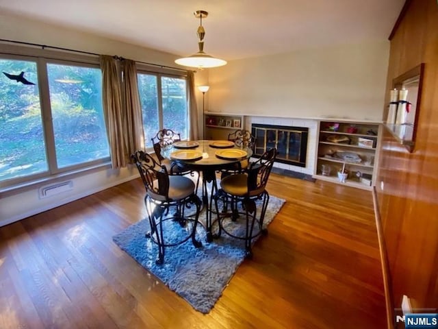 dining area featuring a fireplace, wood finished floors, visible vents, and baseboards