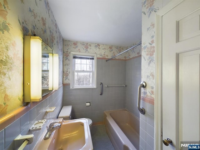 full bathroom featuring tile walls, sink, tiled shower / bath combo, and toilet