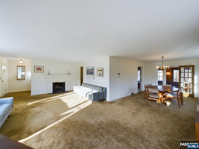 unfurnished living room featuring a brick fireplace, a notable chandelier, and carpet floors