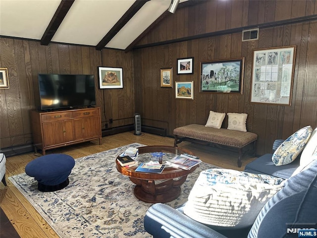 living area featuring vaulted ceiling with beams, wood walls, light wood-type flooring, and visible vents