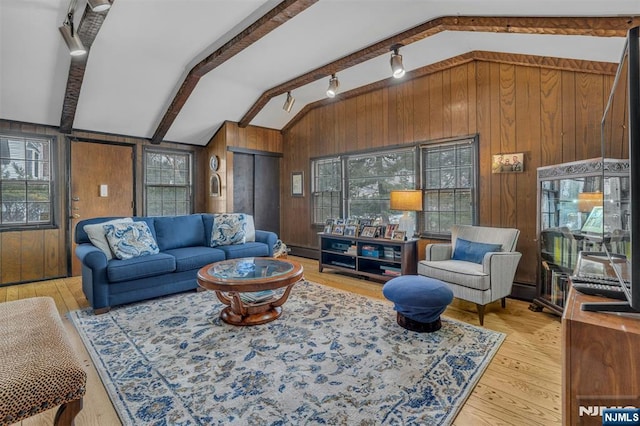 living room with lofted ceiling with beams, a baseboard heating unit, light wood finished floors, and wood walls