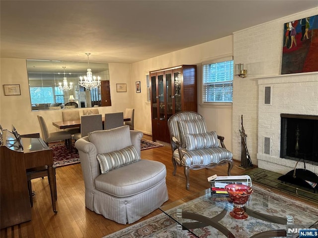 living area with a brick fireplace, wood finished floors, and a notable chandelier