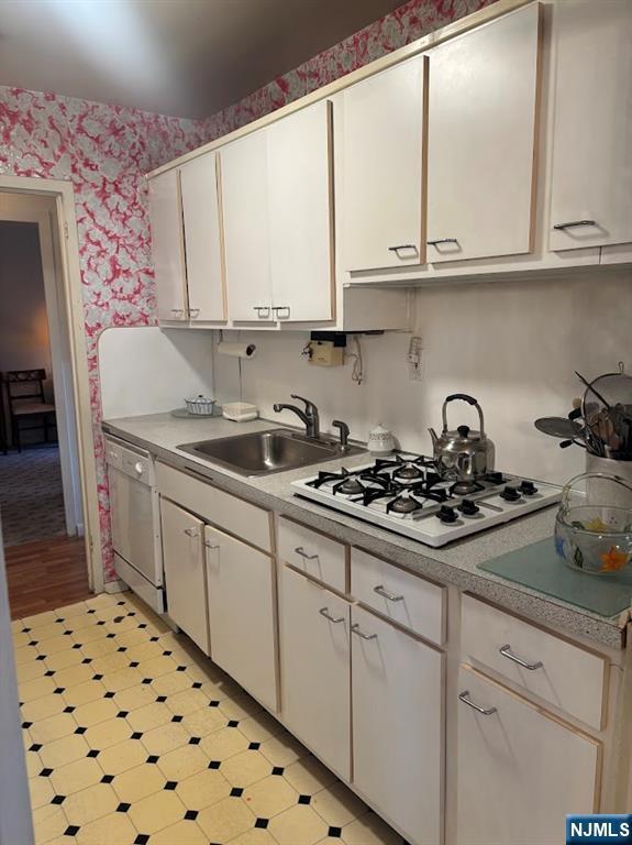 kitchen with white cabinetry, white appliances, and sink