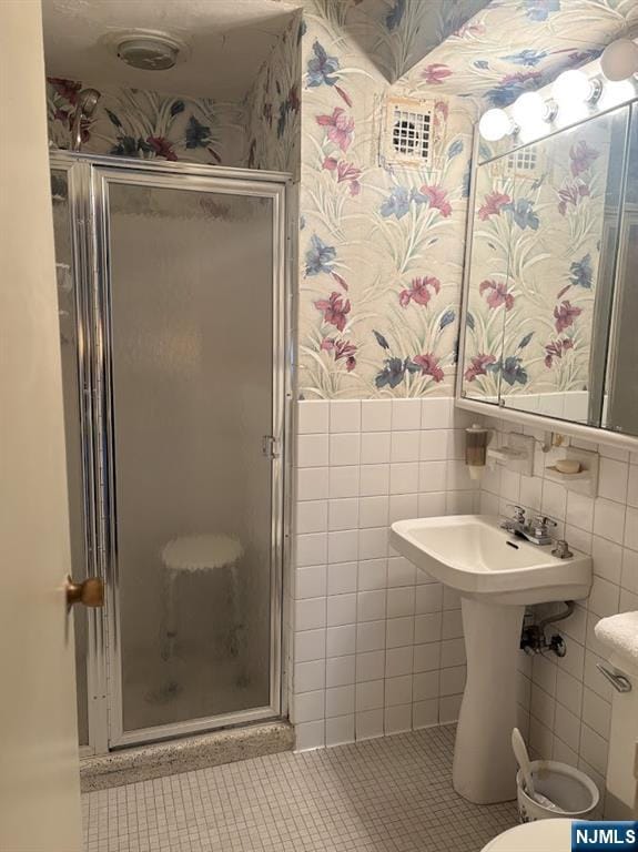 bathroom with tile walls, an enclosed shower, and tile patterned floors