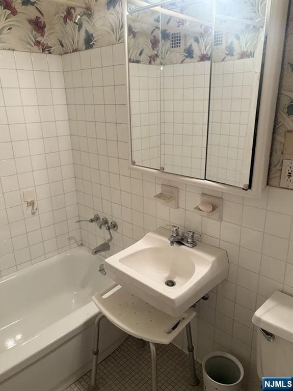 bathroom featuring sink, tile walls, tile patterned flooring, a bath, and toilet