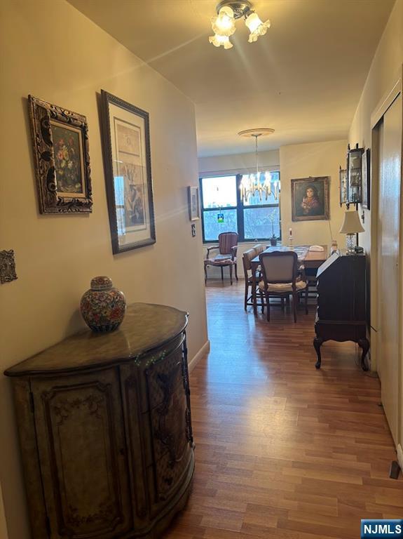 hallway with hardwood / wood-style floors and a chandelier