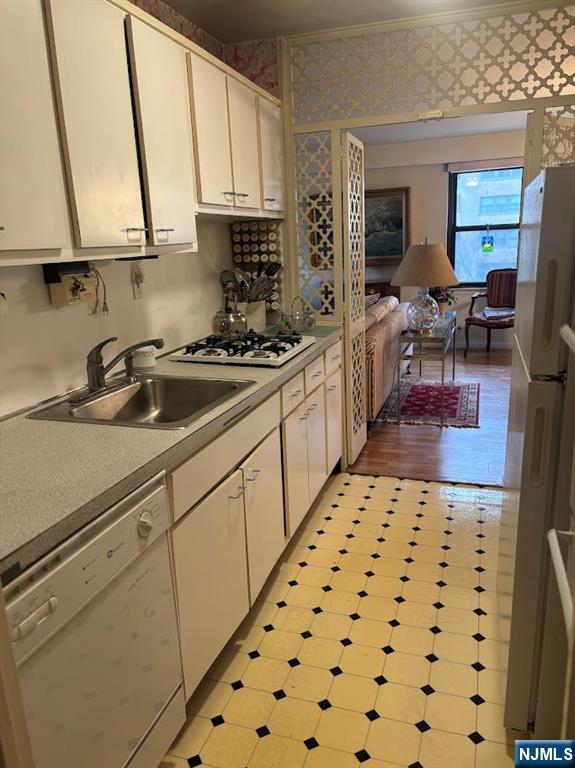 kitchen with white cabinetry, sink, white appliances, and crown molding