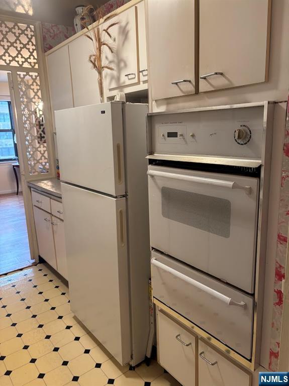 kitchen featuring white refrigerator and white cabinetry