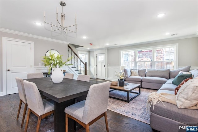 dining space featuring dark wood-type flooring, crown molding, and an inviting chandelier