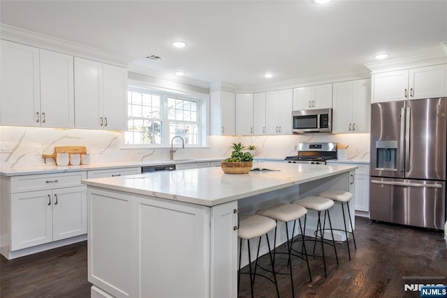 kitchen with dark hardwood / wood-style floors, a center island, white cabinets, and appliances with stainless steel finishes