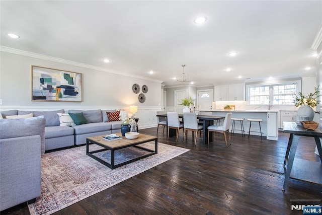 living room with ornamental molding, dark hardwood / wood-style floors, sink, and an inviting chandelier