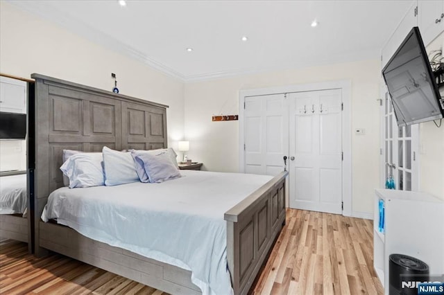 bedroom featuring crown molding, light hardwood / wood-style flooring, and a closet