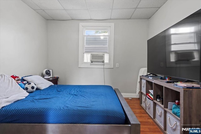 bedroom featuring cooling unit, a paneled ceiling, and hardwood / wood-style floors