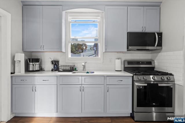 kitchen with tasteful backsplash, appliances with stainless steel finishes, and sink