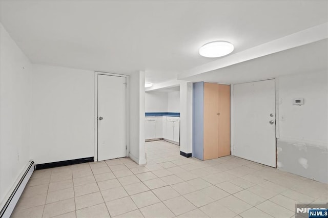 tiled spare room featuring a baseboard heating unit