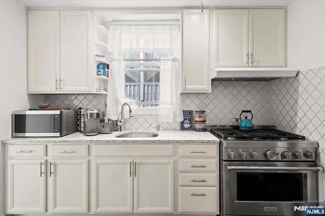 kitchen with sink, backsplash, stainless steel appliances, light stone countertops, and white cabinets