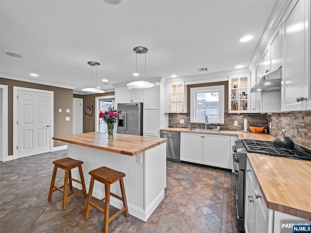 kitchen with butcher block countertops, white cabinetry, decorative light fixtures, a center island, and appliances with stainless steel finishes